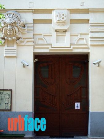 The entrance of the building, the house number carved into the facade above it