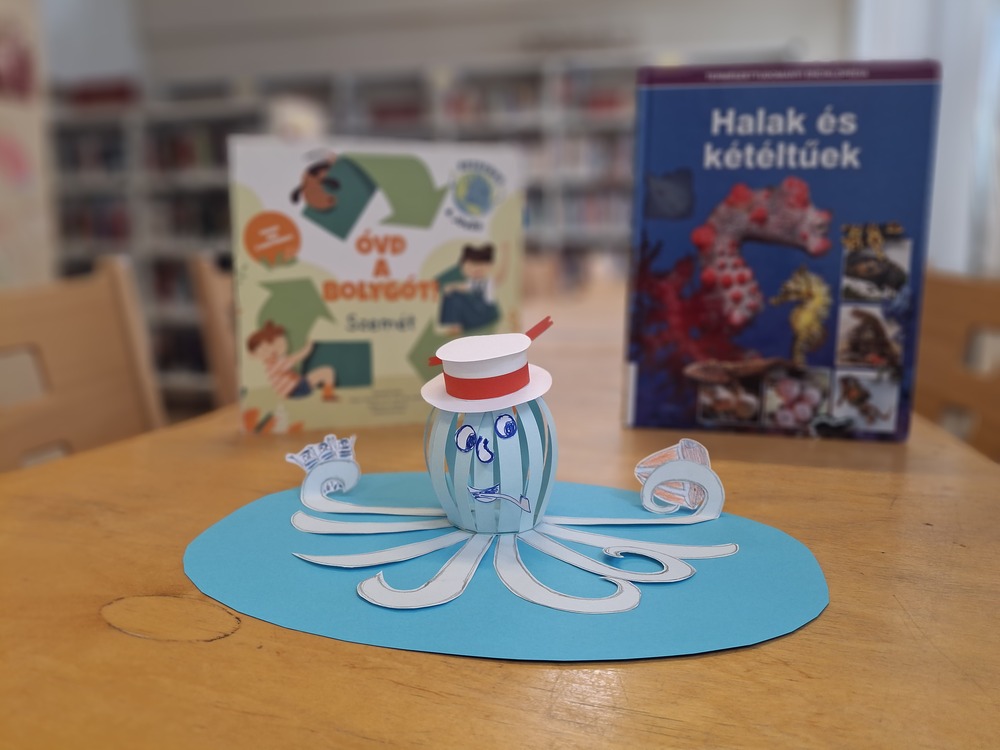 Pipázó papírpolip, mögötte óceán témájú könyvek