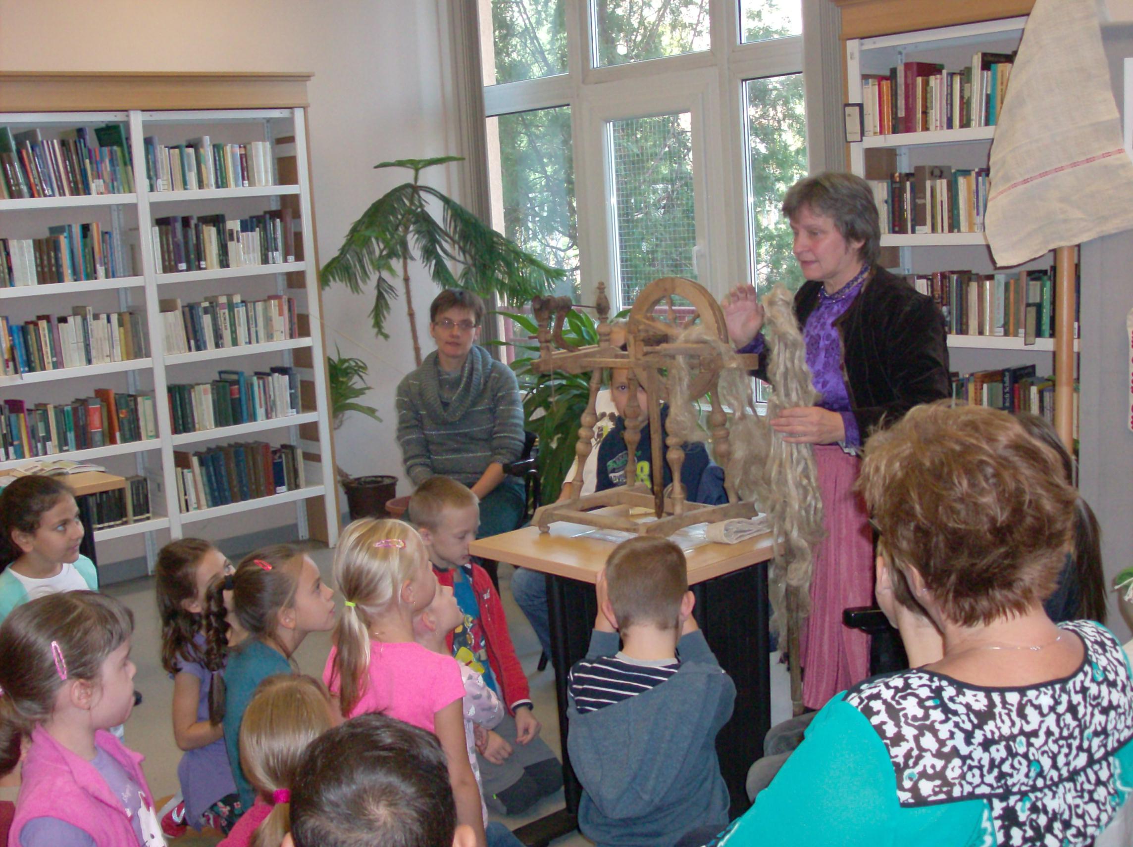 Gyerekek és előadó rokkával a könyvtárban