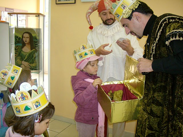 Mátyás királynak öltözött férfi kosarából húz egy kislány egy ajándékot