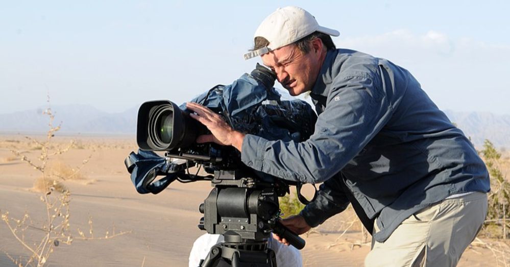 Egy sivatagi növényről készít felvételt egy kamerát tartó férfi 