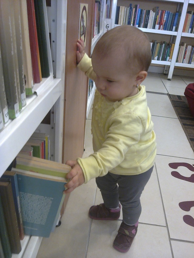 A baby is watching (browsing) books.