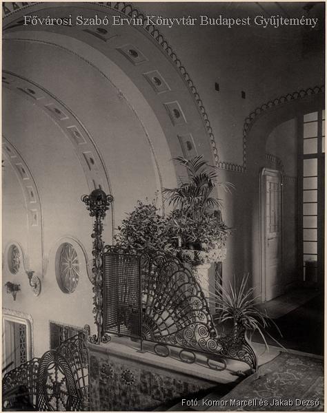 Díszes vasrács és szobanövények a lépcsőházi feljáró fölött