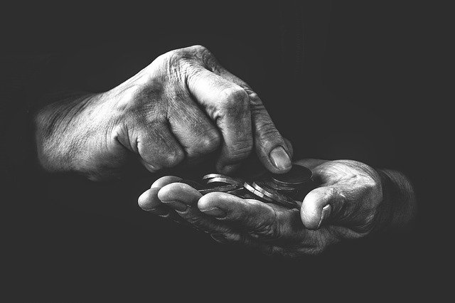 Fekete-fehér imázskép egy kézről, amiben aprópénzt tart
