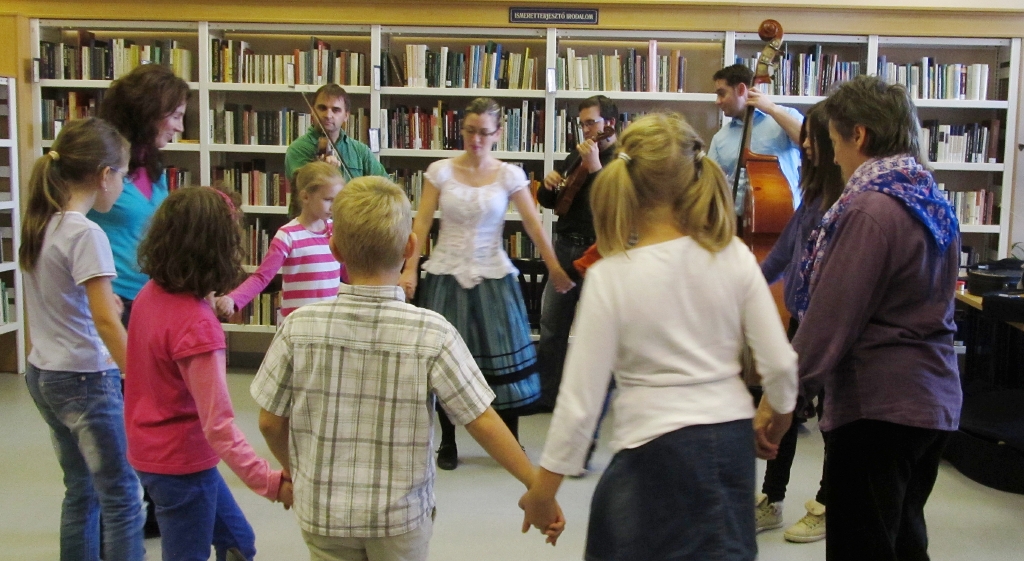 A Magyar Virtus Zenekar zenéjére körtáncot járnak gyerekek